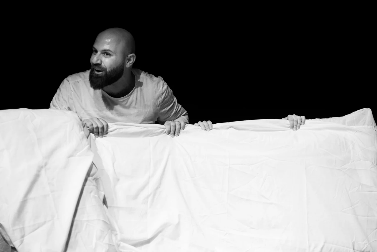 Fabio Manniti in scena in Geminga, dietro un telo bianco